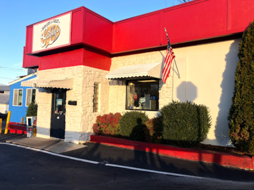 Exterior of a restaurant with a red and white facade, featuring a sign that reads "Lenny's" and an American flag.