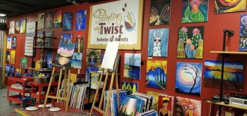 Art studio interior featuring colorful paintings on the walls, easels, and art supplies in a creative space.