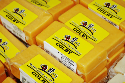 Blocks of Colby cheese from Sweetwater Valley Farm, neatly packaged with labels on a display.