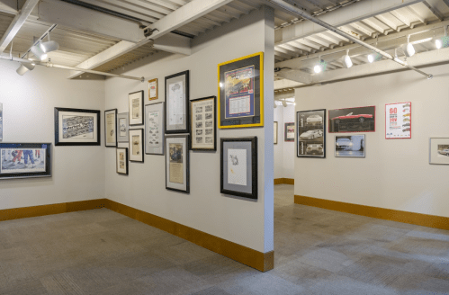 A gallery wall featuring various framed photographs and documents in a well-lit exhibition space.