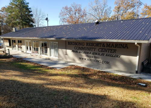 Exterior of the Birdsong Resort & Marina Community Center, featuring a sign and a grassy area in front.
