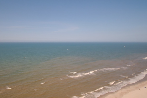A serene beach scene with gentle waves lapping at the shore under a clear blue sky.