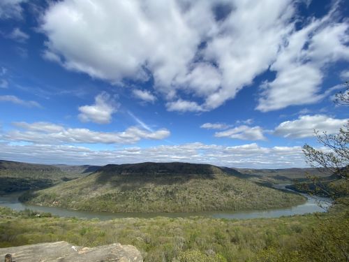 A scenic view of a river winding through lush green hills under a partly cloudy sky.