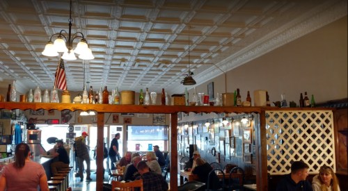 A cozy restaurant interior with wooden tables, vintage decor, and patrons enjoying their meals.