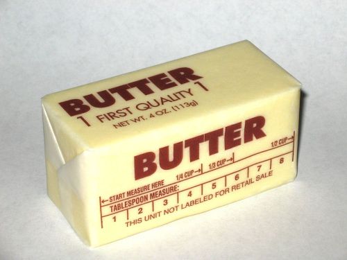 A stick of butter with measurement markings and "First Quality" label, weighing 4 oz.