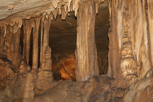 Stalactites and stalagmites in a dimly lit cave, showcasing unique rock formations and textures.