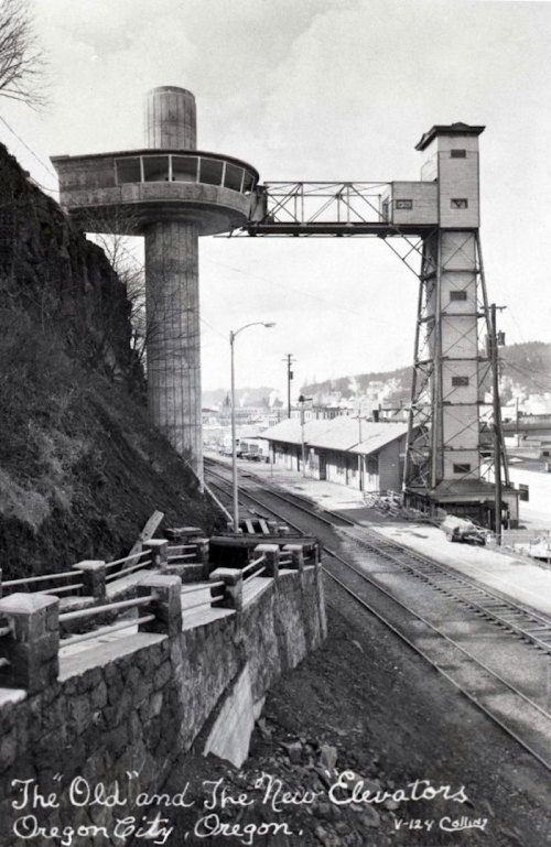 Black and white photo of old and new elevators in Oregon City, with a railway and buildings in the background.