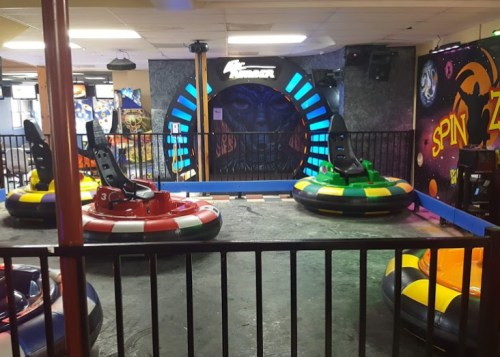 A colorful bumper car arena with several bumper cars and a vibrant, themed backdrop.