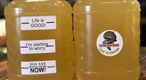 Two clear containers with yellow liquid, featuring labels that read "Life is GOOD!", "I'm starting to worry!", and "S.O.S S.O.S Need to reorder NOW!" along with a logo for Los Aztecas.