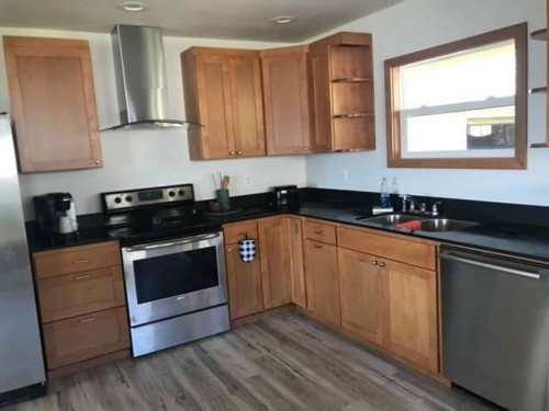 Modern kitchen with wooden cabinets, stainless steel appliances, and a black countertop. Bright and spacious design.