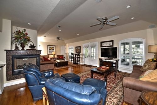 Spacious living room with a fireplace, comfortable seating, and large windows, featuring wooden floors and decorative accents.