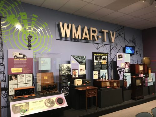 Exhibit showcasing the history of WMAR-TV with vintage radios, televisions, and informative displays.