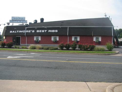 A red and black restaurant building with "Baltimore's Best Ribs" sign, surrounded by flowers and a road in front.