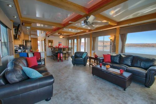 Spacious living area with leather sofas, a dining table, and large windows overlooking a scenic water view.