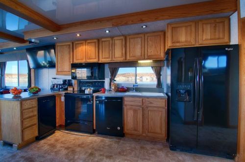 Modern kitchen with wooden cabinets, black appliances, and a scenic view through large windows.