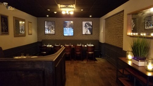 Cozy restaurant interior with wooden seating, brick walls, and artistic decor, featuring tables set for dining.