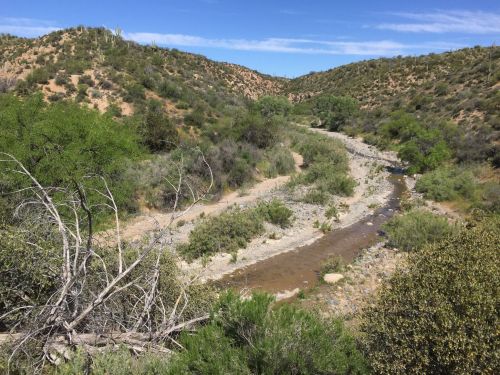 A winding river flows through a dry, hilly landscape with sparse vegetation under a clear blue sky.