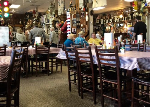 A bustling diner with checkered tables, vintage decor, and patrons enjoying their meals in a lively atmosphere.