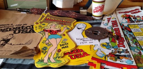 Colorful vintage items from Dogpatch USA, including banners, a weight, and a paper bag featuring Daisy Mae.