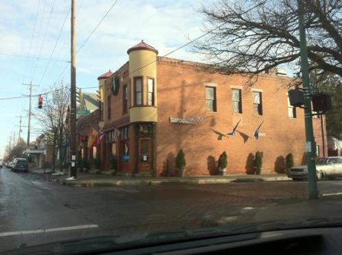 A brick building with a turret, decorated for the holidays, located at a street corner with traffic signals.