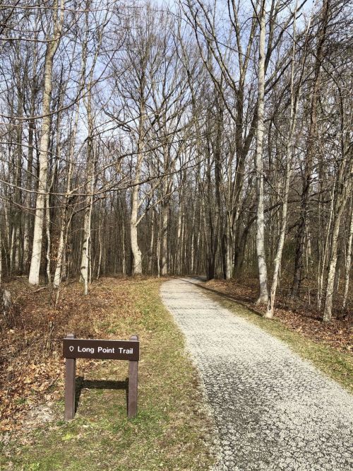 A gravel path leads through a wooded area, with a sign for Long Point Trail visible on the left.