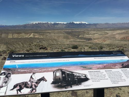 A scenic view of mountains and valleys with an informational sign about the area's history and geology in the foreground.