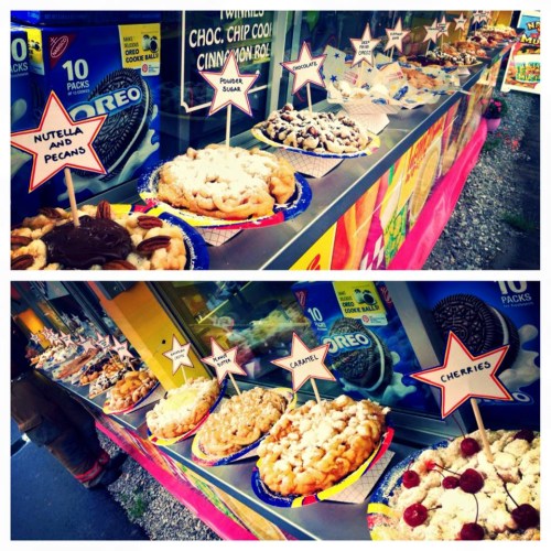 A colorful display of various desserts, including funnel cakes topped with Nutella, powdered sugar, and cherries.
