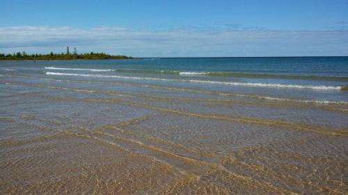 A serene beach scene with gentle waves lapping at the shore under a clear blue sky.