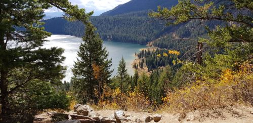 Scenic view of a lake surrounded by mountains and trees, with autumn foliage along the shoreline.