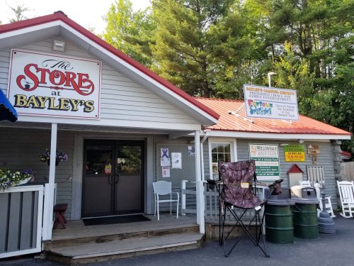 Exterior of "The Store at Bayley's," featuring a red roof, sign, and outdoor seating.