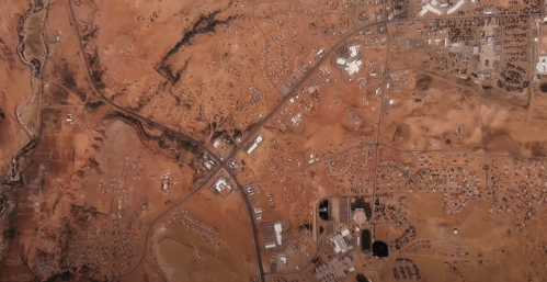 Aerial view of a desert landscape with roads, buildings, and sparse vegetation.