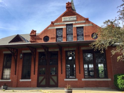Historic red brick building with large windows and decorative gables, featuring the name "Macon" prominently displayed.