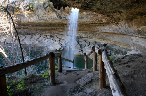 A serene waterfall cascades into a tranquil pool, surrounded by rocky cliffs and lush greenery.