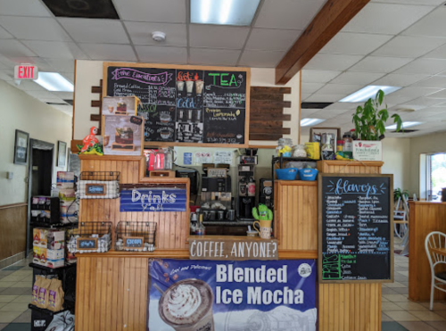 A cozy café counter with a menu board, coffee machines, and various drink options displayed.