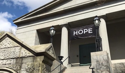 A stone building with columns and a banner reading "HOPE" hanging from the front.