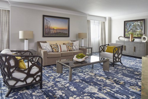 A stylish living room featuring a sofa, armchairs, coffee table, and decorative artwork in a bright, modern design.