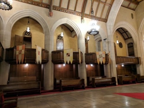 Interior of a grand hall with arched ceilings, wooden balconies, and decorative banners hanging from the walls.