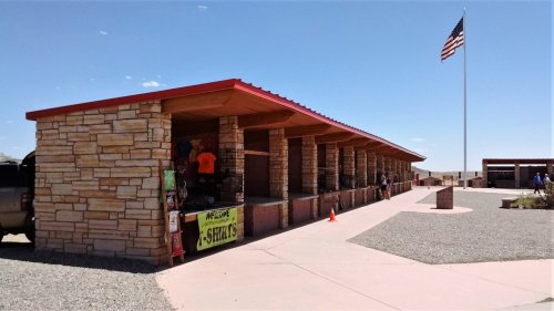 A stone building with a red roof, featuring a gift shop and an American flag flying in the background.
