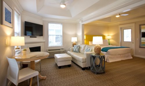 Cozy hotel room featuring a bed, seating area, table, and modern decor with natural light.