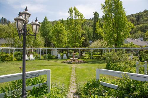 A serene garden with lush greenery, a stone path, and a decorative lamp post under a clear blue sky.