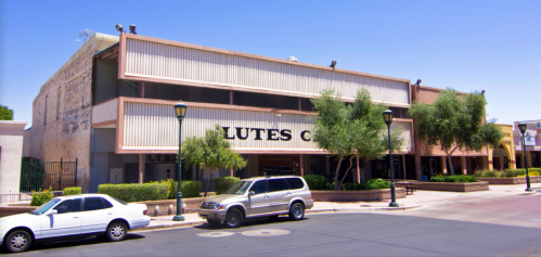 A modern building with large windows and a sign reading "Lutes Co," surrounded by trees and parked cars.
