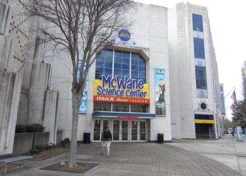 Exterior view of the McWane Science Center, featuring the IMAX Dome Theater entrance and a nearby tree.