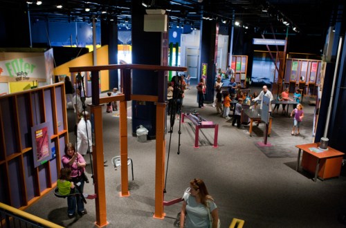 A vibrant science museum exhibit with interactive displays and visitors exploring various hands-on activities.