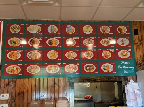 Menu board featuring various dishes with prices, displayed on a red background in a restaurant.