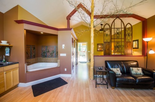 Cozy interior featuring a living area with a leather couch, a bathroom nook, and decorative elements like a tree branch.