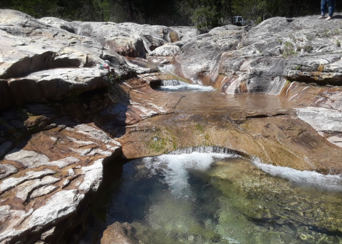 A serene rocky landscape with clear water flowing over smooth stones, creating small pools and gentle cascades.