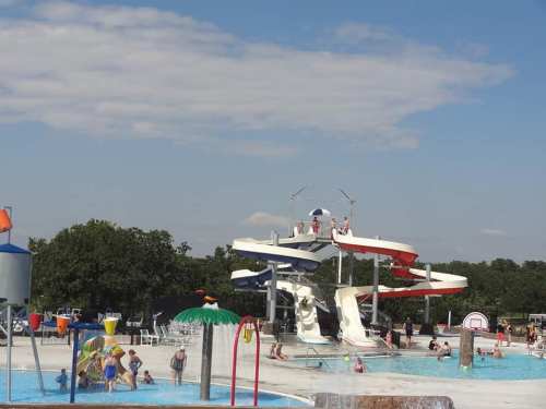A busy water park with colorful slides, pools, and people enjoying the sun on a clear day.