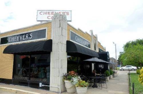 Exterior view of Cheever's Cafe, featuring a brick building, awnings, outdoor seating, and a sign above.