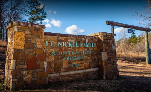 Sign for J.T. Nickel Family Nature & Wildlife Preserve, featuring stone structure and natural surroundings. Established 2006.