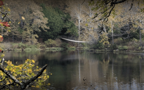 A serene lake surrounded by autumn trees, reflecting the colorful foliage on the water's surface.